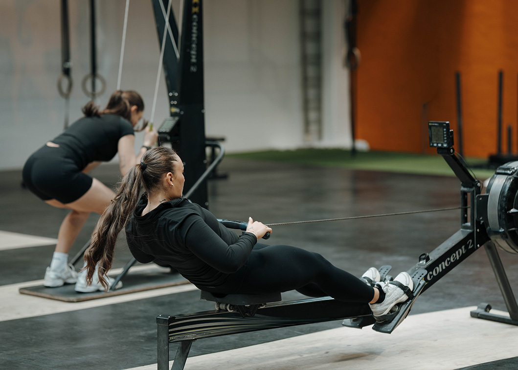 Coachen ror på en romaskine i et fitnesscenter